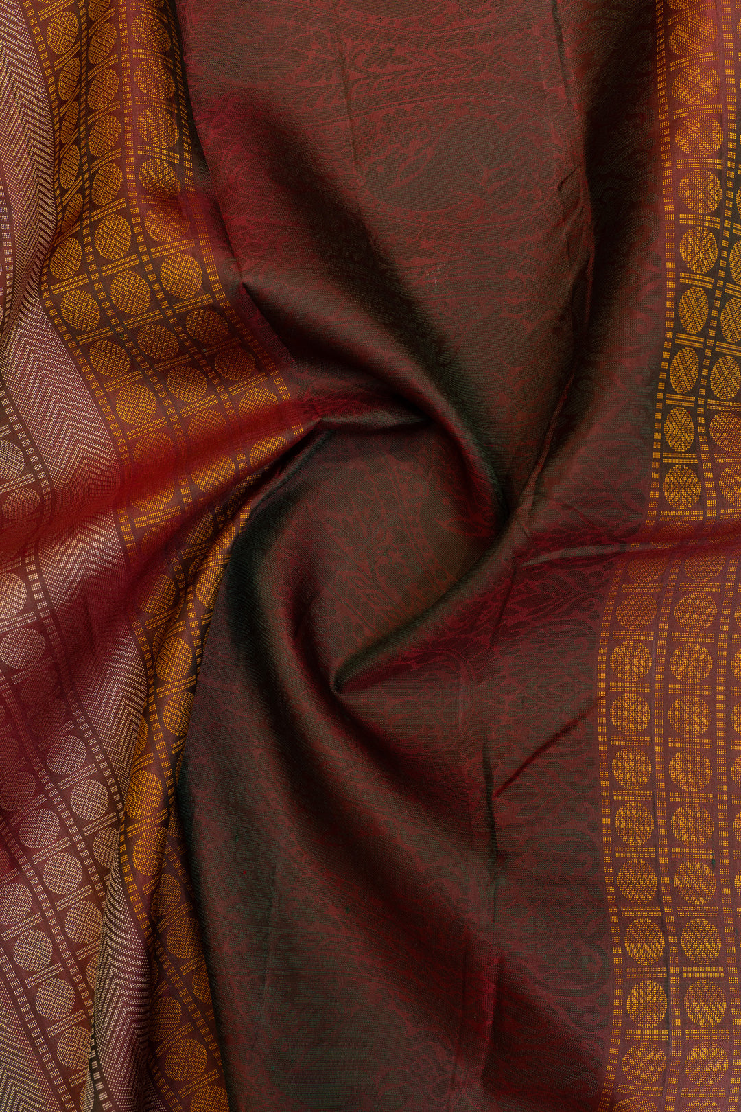 Close-up of a maroon fabric with intricate patterns and borders