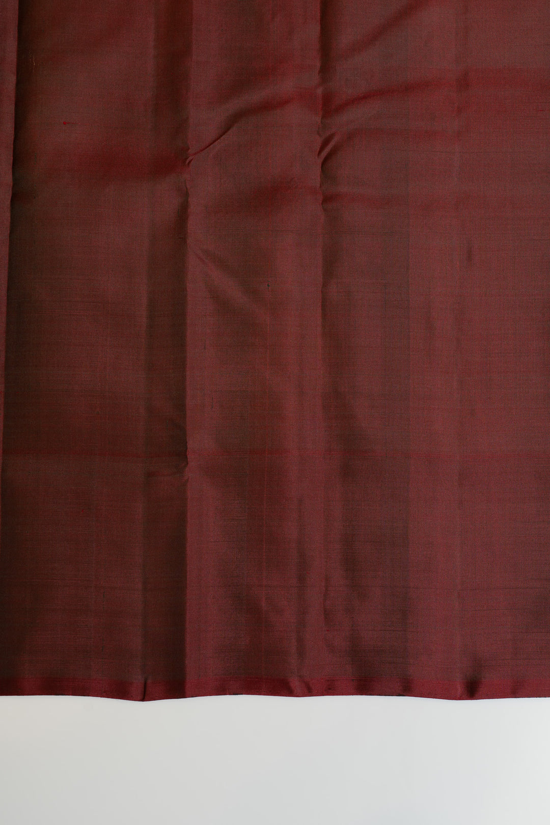 Close-up of dark red fabric with a textured pattern on a white background