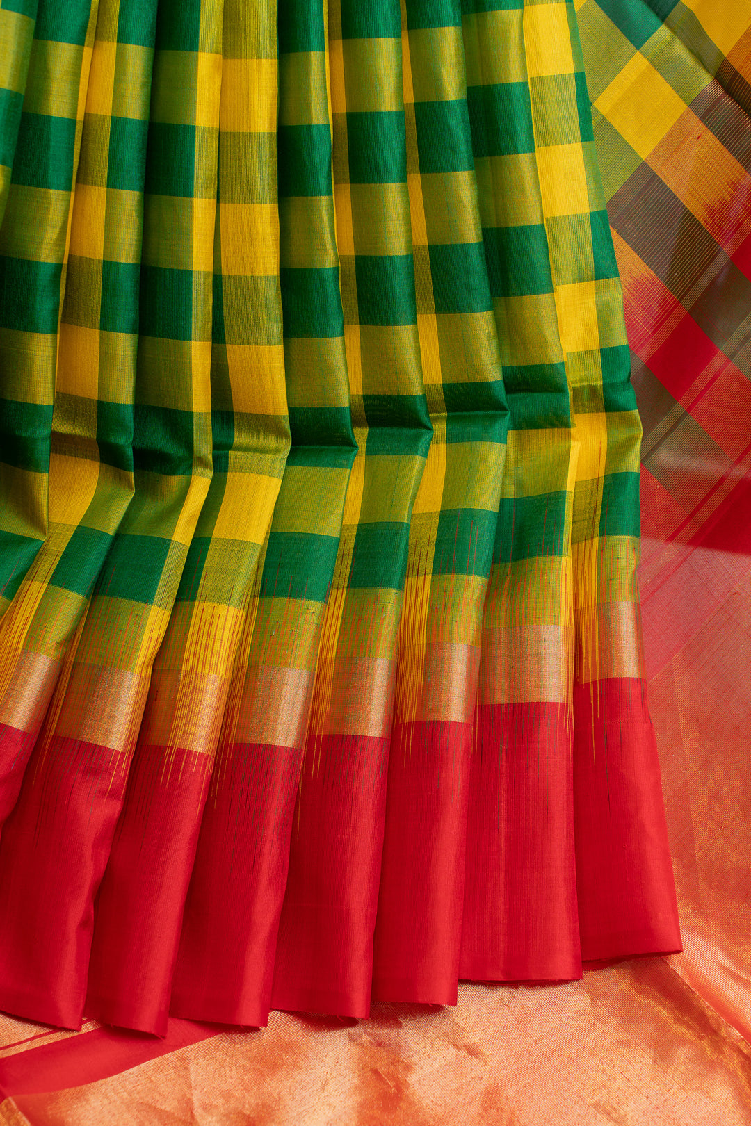 Colorful checkered fabric with green, yellow, and red pattern on a plain background