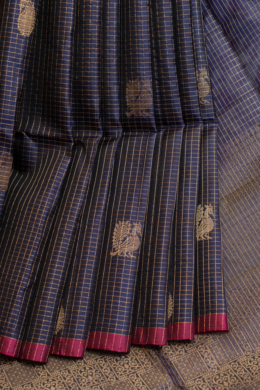 Blue and black checkered fabric with gold patterns and red borders on a textured surface.