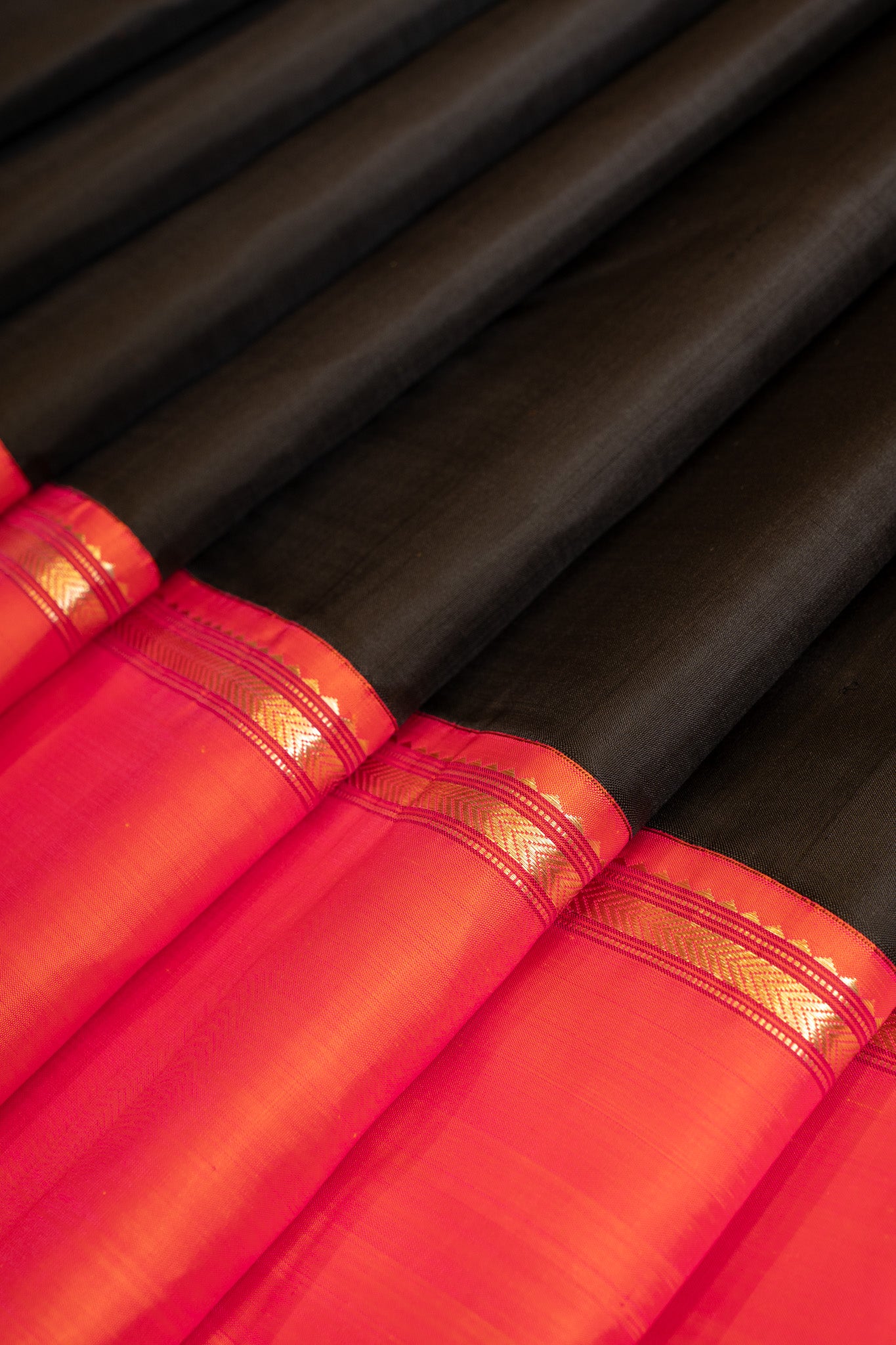 Close-up of the pleats of a black and peach pure Kanchipuram silk saree with fine craftsmanship