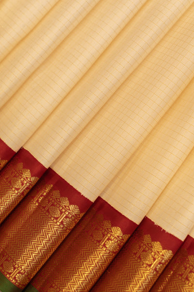 Close-up of the pleats of an off white Kanjivaram silk saree with intricate zari checks and a maroon border