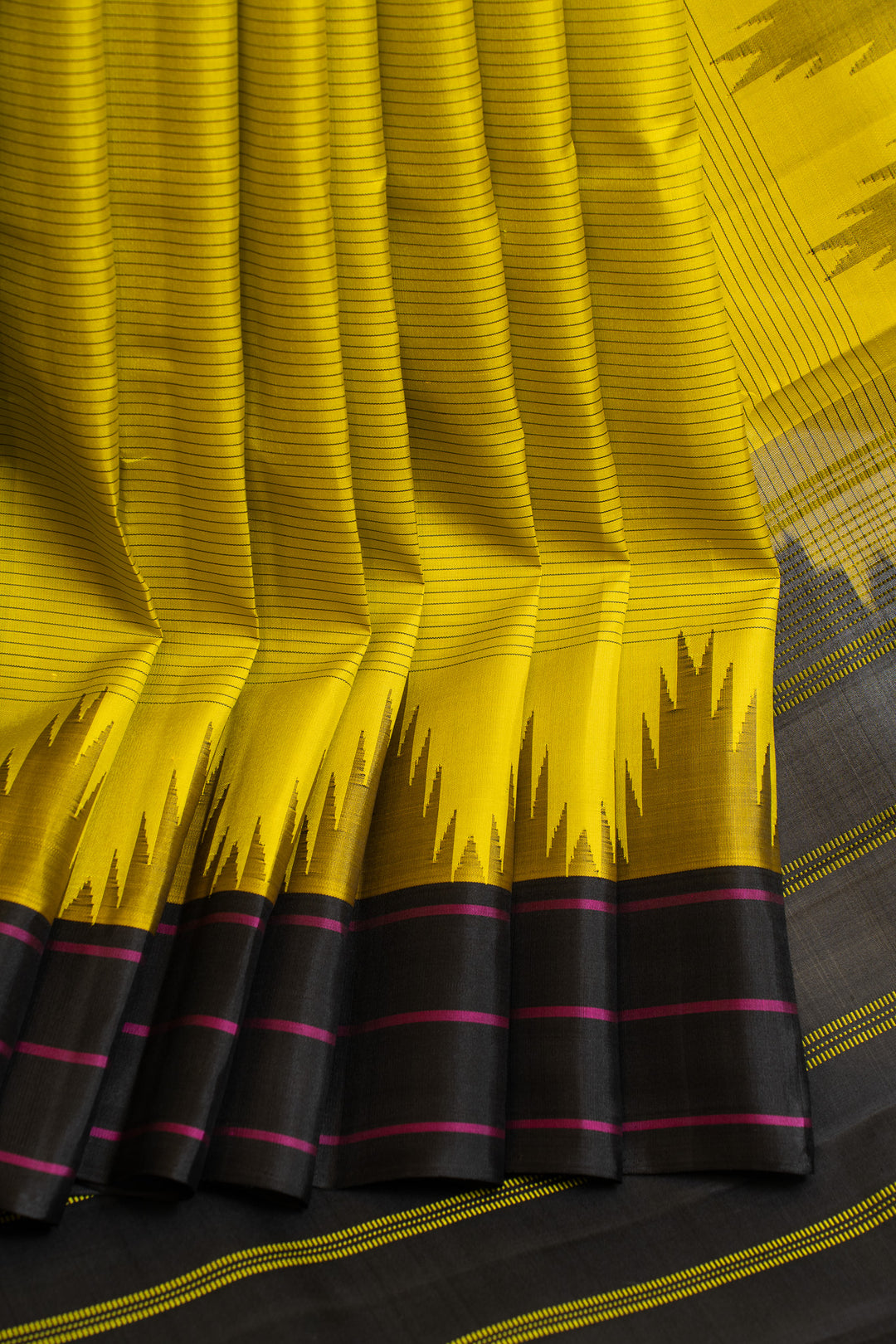 Yellow and black patterned fabric with pink stripes on a wooden surface