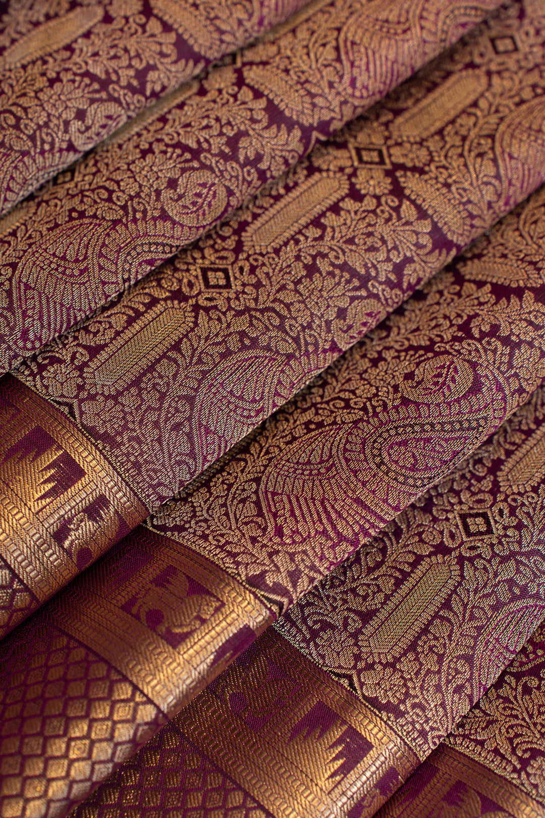 Close-up of patterned fabric with intricate designs in gold and purple.