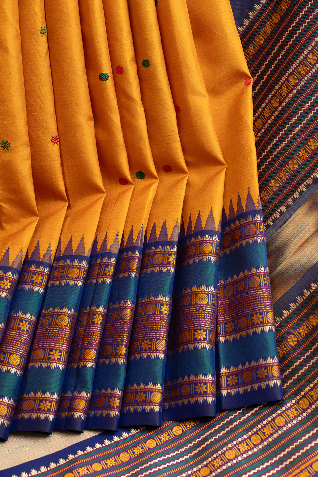 Yellow saree with blue and multicolor border on a patterned fabric background