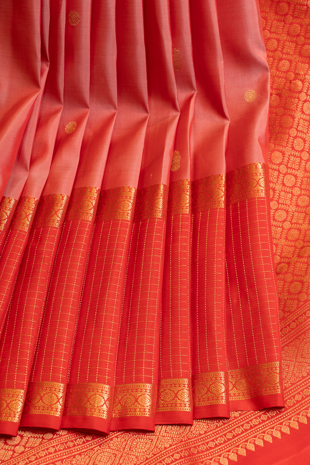 Red saree with gold border on a matching fabric background