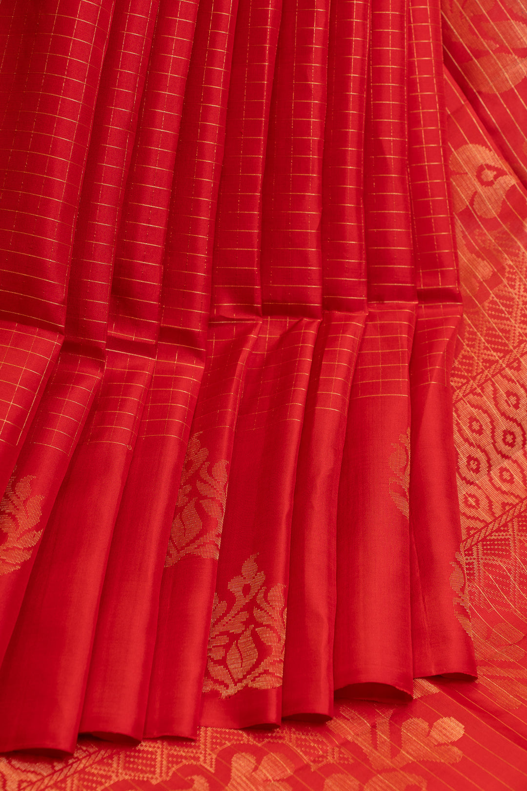 Red fabric with gold patterns and pleats on a matching background